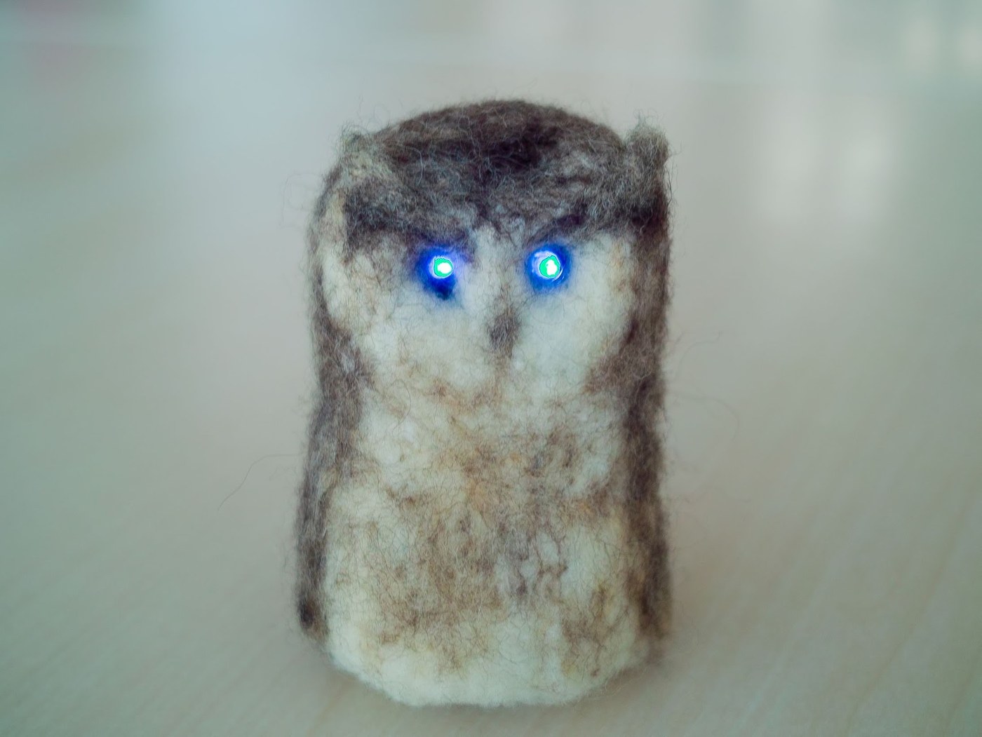 A felt owl with glowing blue eyes