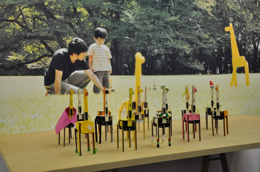 Many giraffes lined up at a workshop