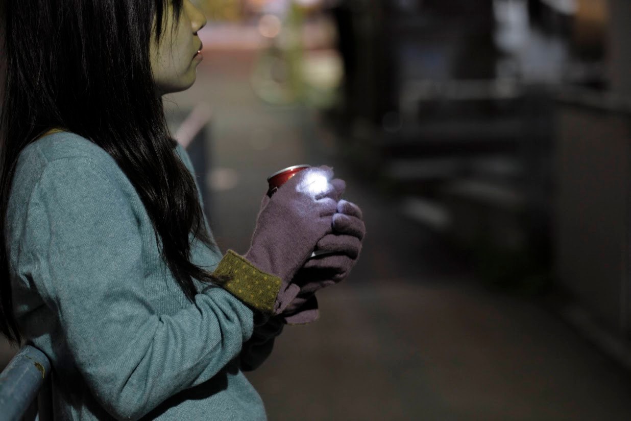 夜、手袋をはめた手で缶を包み込むように持ち、指輪が光っている様子